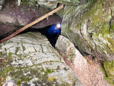 A spelunker wearing a headlamp looks up from inside a cave at Warsaw Caves Conservation Area