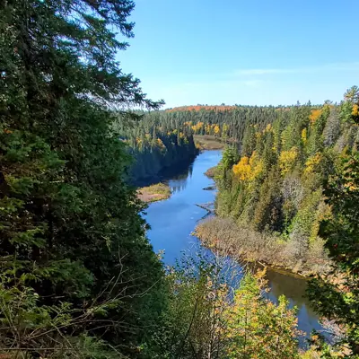 The view from the top of the Lookout Trail at Warsaw Caves Conservation Area with the Indian River flowing by far below, surrounded by forests.